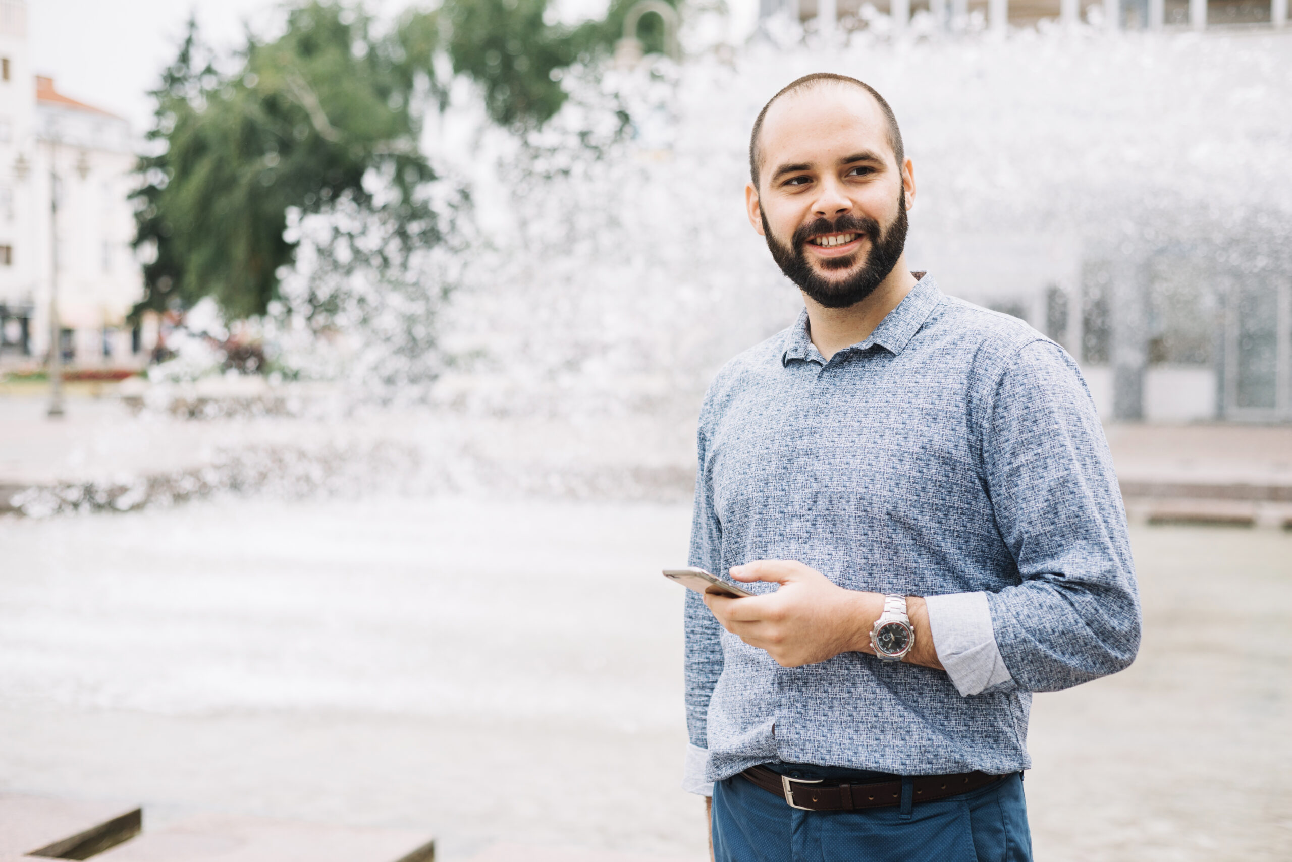 smiling businessman with phone downtown 1 scaled